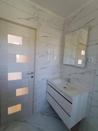 a white bathroom with a sink and a mirror at Sunčani Breg Apartments Vrdnik in Vrdnik