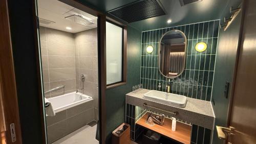 a bathroom with a sink and a mirror and a tub at Hotel Keihan Asakusa in Tokyo