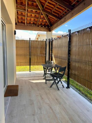 a patio with a table and chairs and a fence at Super studio aux portes de Bordeaux ! in Gauriaguet