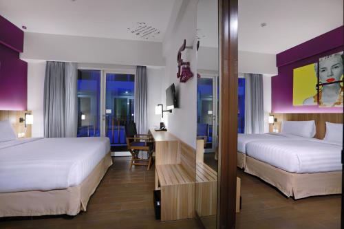 a hotel room with two beds and a desk at Fame Hotel Sunset Road in Kuta
