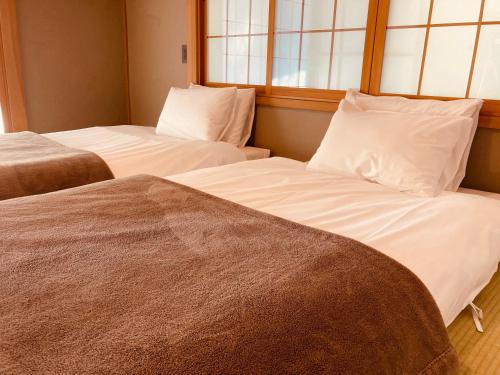 two beds sitting next to each other in a room at 天然温泉が満喫できる一棟貸宿 little villa 柊日 in Azumino