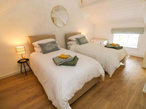 two beds in a bedroom with a mirror on the wall at Graig Goch in Burry Port