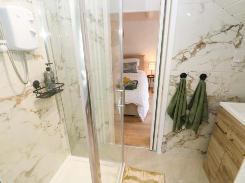 a bathroom with a shower and a bedroom with a bed at Graig Goch in Burry Port
