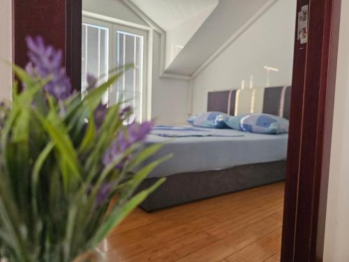 a bedroom with a bed and a vase with purple flowers at Apartmani Mašić Trebinje in Trebinje