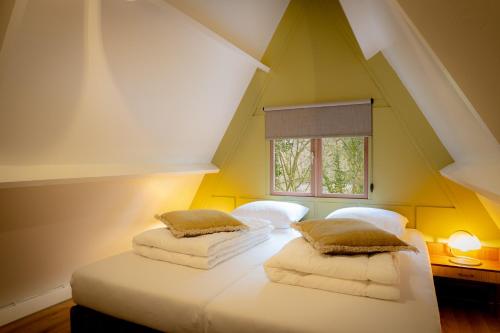 two beds in a room with yellow walls and a window at Boshuisje Rekem - Nirvana in Lanaken