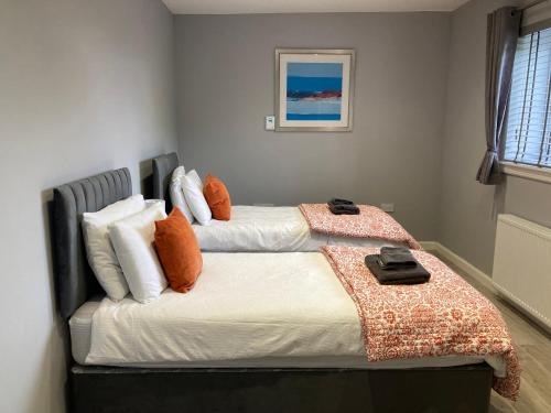 a bedroom with two beds with orange and white pillows at The Dairy in Airdrie