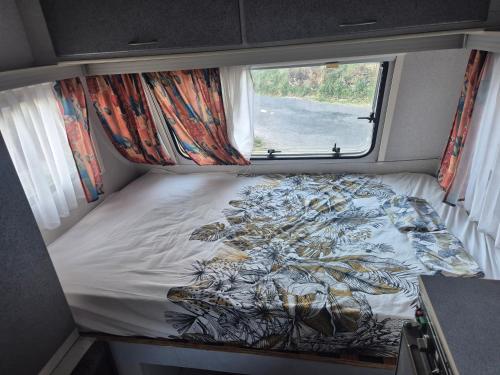 a bed in a small room with a window at Caravane dans les Cévennes in Saint-Germain-de-Calberte