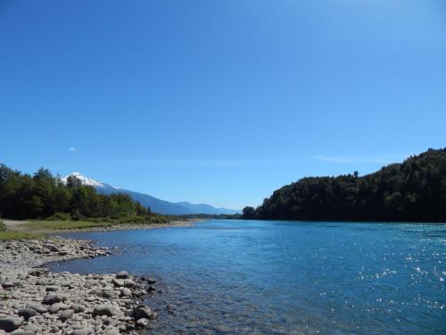a river with rocks and trees in the background at Cabañas Nutrias Patagonicas in Puelo
