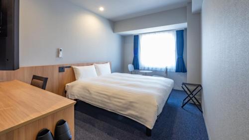 a bedroom with a bed and a desk and a window at Toyoko Inn Kure-eki in Kure