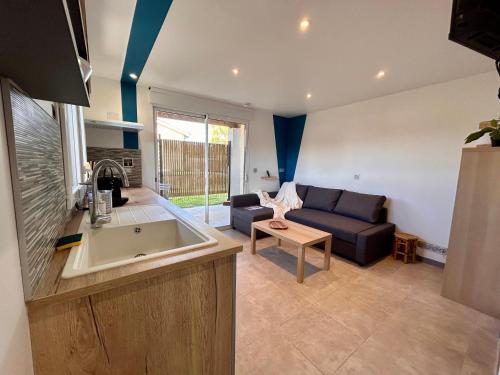 a kitchen and living room with a couch and a table at Super studio aux portes de Bordeaux ! in Gauriaguet