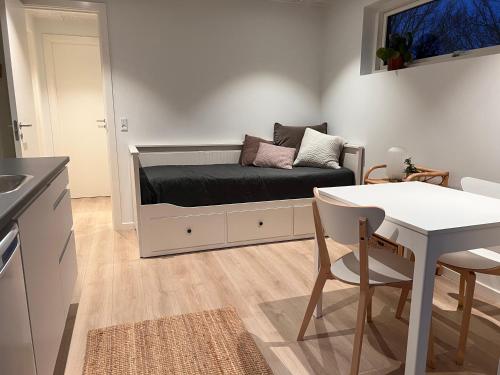 a room with a bed with a table and a couch at Cosy guesthouse in peaceful garden surroundings in Silkeborg