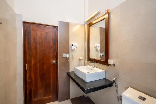 a bathroom with a sink and a mirror and a toilet at Serene Park Hotel By Ark in Tissamaharama