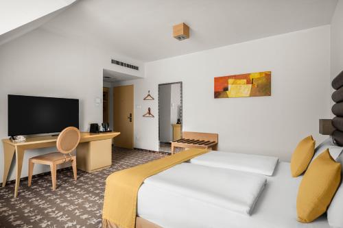 a hotel room with a bed and a desk and a tv at Buda Castle Hotel Budapest in Budapest