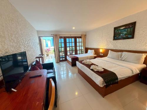 a hotel room with two beds and a flat screen tv at Blue Neptuna Hotel Patong in Patong Beach