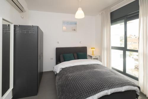 a bedroom with a bed and a large window at Assuta studio in Tel Aviv