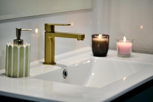 a bathroom sink with a gold faucet and two candles at Malanda Falls Retreat in Malanda