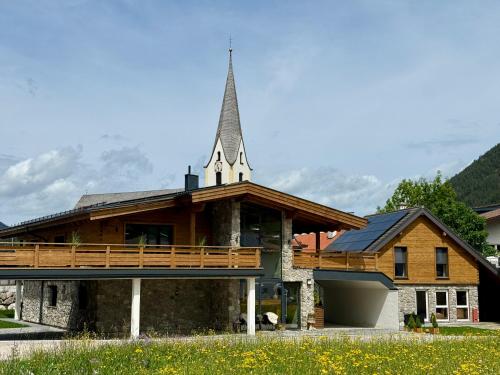 eine Kirche mit einem Kirchturm auf einem Gebäude in der Unterkunft Alprocks Alvaresort in Bichlbach