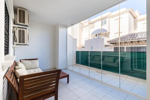 a living room with a bench and a large window at Playa del Pinet 2 in La Marina