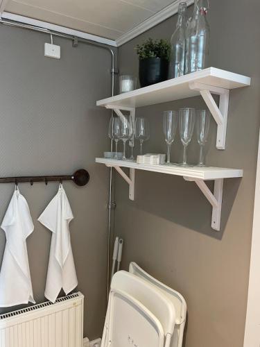 a bathroom with white shelves with glasses and a toilet at Guesthouse Holmen in Färgelanda