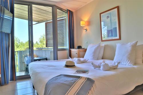 a bedroom with a large white bed with a large window at SOWELL HOTELS Ardèche in Grospierres