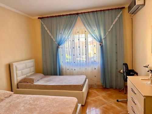a bedroom with two beds and a window with blue curtains at Double Triple Rooms With Lake View balcony in Pogradec