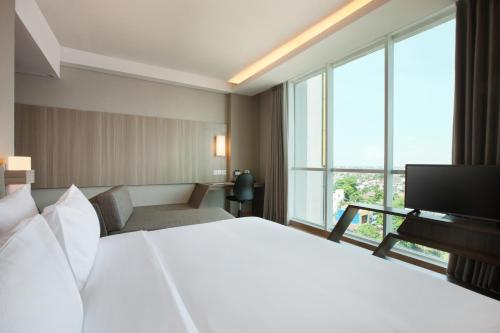 a hotel room with a bed and a television at Hotel Santika Radial Palembang in Palembang