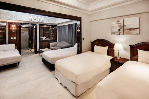 a hotel room with three beds and a couch at Gangnam Artnouveau City in Seoul