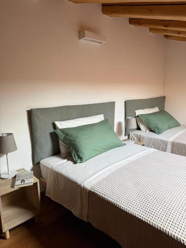 a bedroom with two beds with green pillows at CasAle 1896 in Cavaso del Tomba