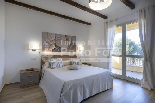 a white bedroom with a bed and a window at Raphael's Boutique Stay in Palau