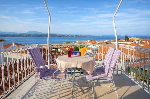a table and chairs on a balcony with a view of the water at Unforgettable Return To Timeless Spetses in Spetses