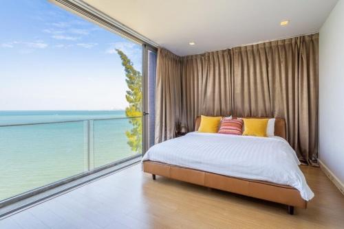 a bedroom with a bed and a large window at Sandbox Beachfront Villa 6 in Ban Krathing Lai