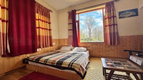 a bedroom with a bed and a window and a table at Akari Inn in Haripūr