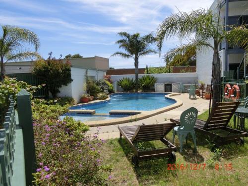 uma piscina num quintal com duas cadeiras em Banjo Paterson Motor Inn em Lakes Entrance