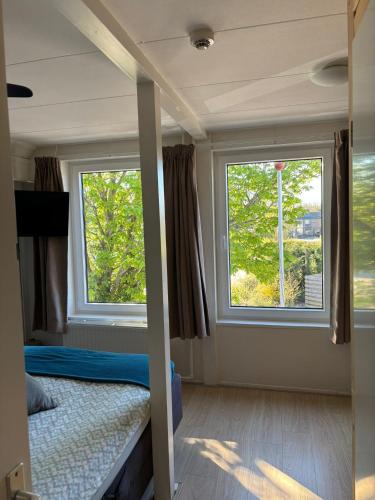 a bedroom with two windows and a bed in it at Bed & Breakfast d'Ouwe Smidse in Kamperland