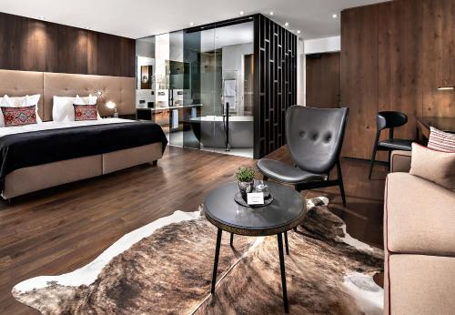 a bedroom with a bed and a chair and a couch at Hotel Alpenroyal - The Leading Hotels of the World in Selva di Val Gardena