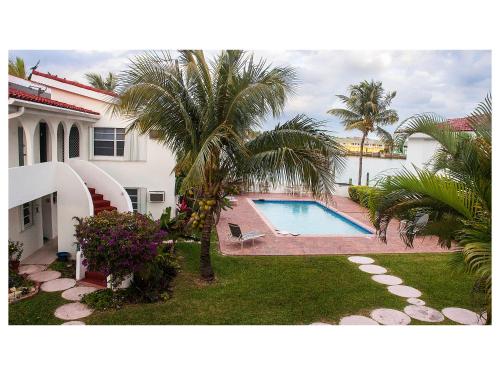 a house with a swimming pool and palm trees at Beauport One-Bedroom Apartment in Freeport