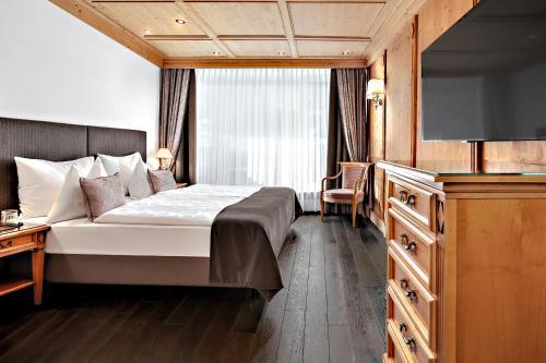 a hotel room with a bed and a flat screen tv at Hotel Alpenroyal - The Leading Hotels of the World in Selva di Val Gardena