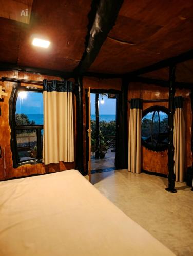 a bedroom with a bed and two windows at Happybeach Sea view Cabin restaurant & beach bar in Tangalle