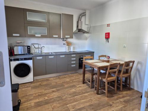 a kitchen with a table and chairs and a sink at Flat near Serra da Arrábida, beaches and Lisbon in Quinta do Conde