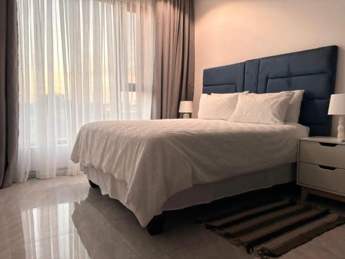 a bedroom with a large bed and a large window at Blue Diamond Luxe in Gaborone