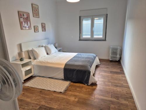 a bedroom with a bed and a fan and a window at Flat near Serra da Arrábida, beaches and Lisbon in Quinta do Conde