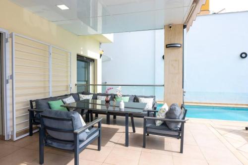 a patio with a table and chairs and a pool at August Villa Málaga. Relax Playa Piscina Coworking in Málaga