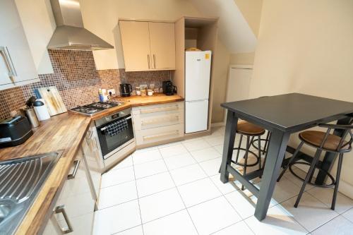 a kitchen with a black table and a white refrigerator at The Mews - Worcester City - House - Gated - Self Check In - Free WIFI - 2 Doubles - TVs in bedrooms - Sleeps 6 - Free Nearby Parking in Worcester