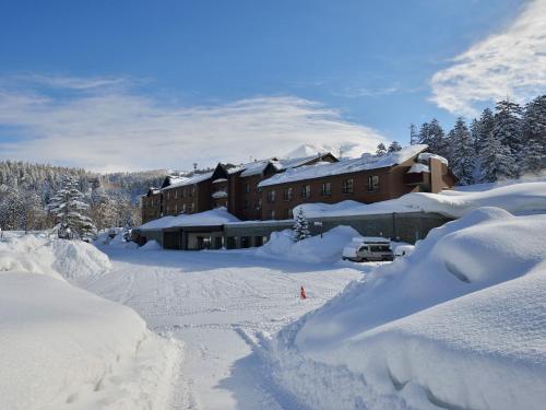 a building covered in snow next to a pile of snow at Higashikawa Asahidake Onsen Hotel Bear Monte in Higashikawa