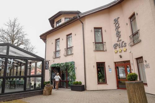 a woman is standing outside of a building at Hotel Pils with Self-Check in in Sigulda