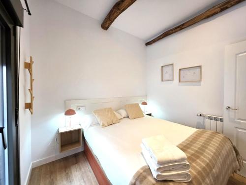 a white bedroom with a bed and a table at El Rincón de Santa Eufemia in Ourense