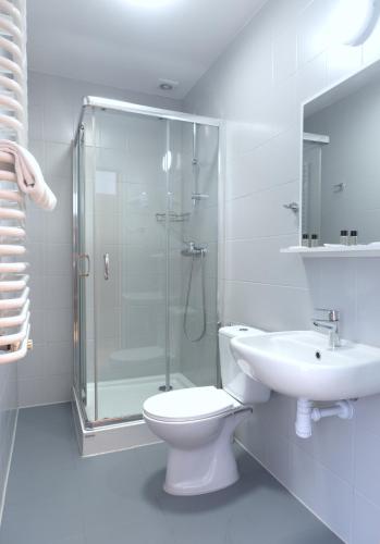 a bathroom with a shower and a toilet and a sink at Hotel Tor Kielce in Kielce