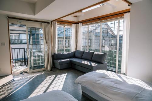 a bedroom with a couch and a large window at Coucou House Gra in Toyooka