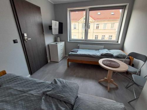 a bedroom with a bed and a table and a window at Noclegi Bielawa in Bielawa
