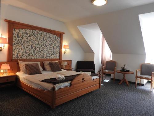 a bedroom with a large wooden bed and chairs at Hotel Argo Lindau in Lindau